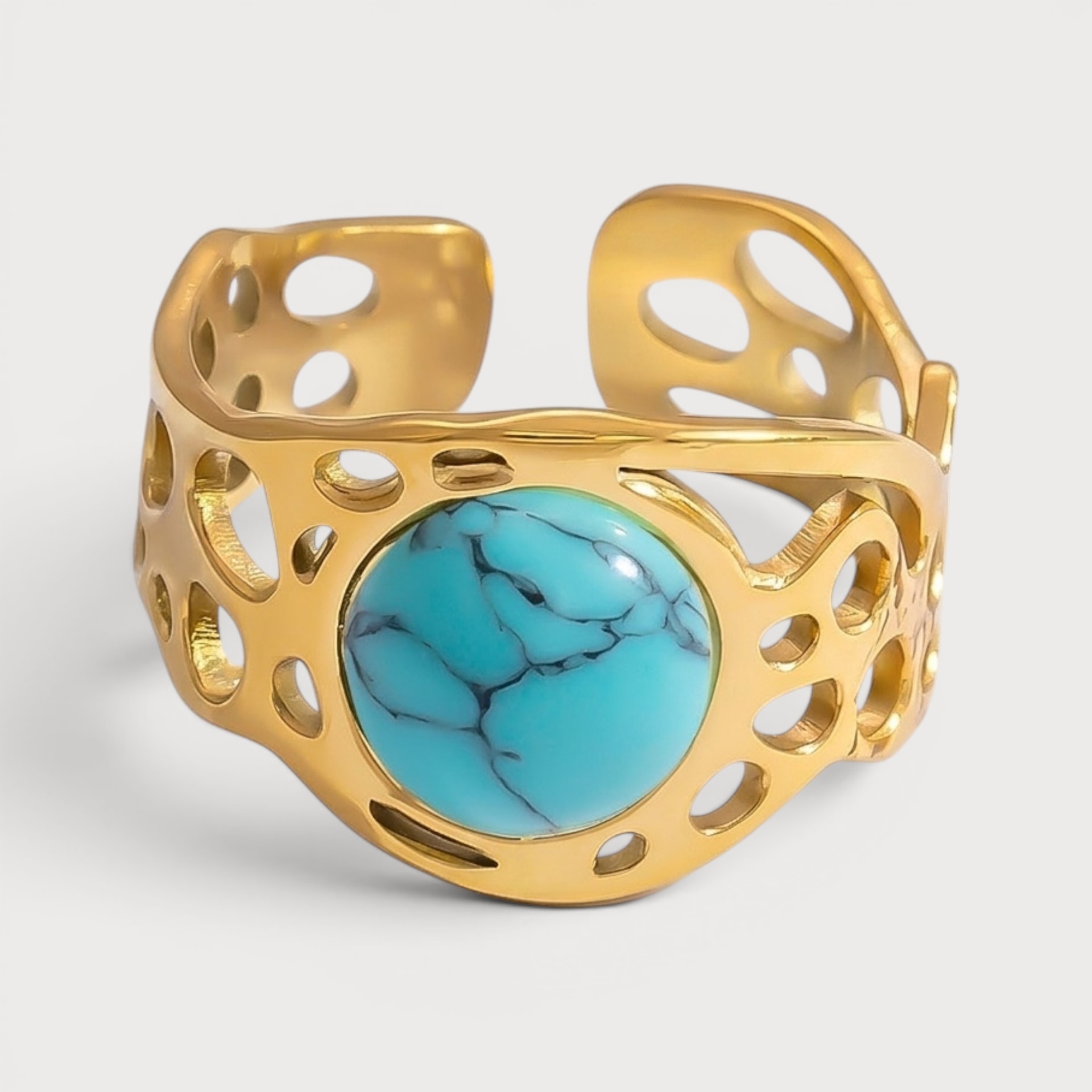 Bague Zoulikha dorée, pierre ronde bleu turquoise sur une large monture à ouvertures irrégulières