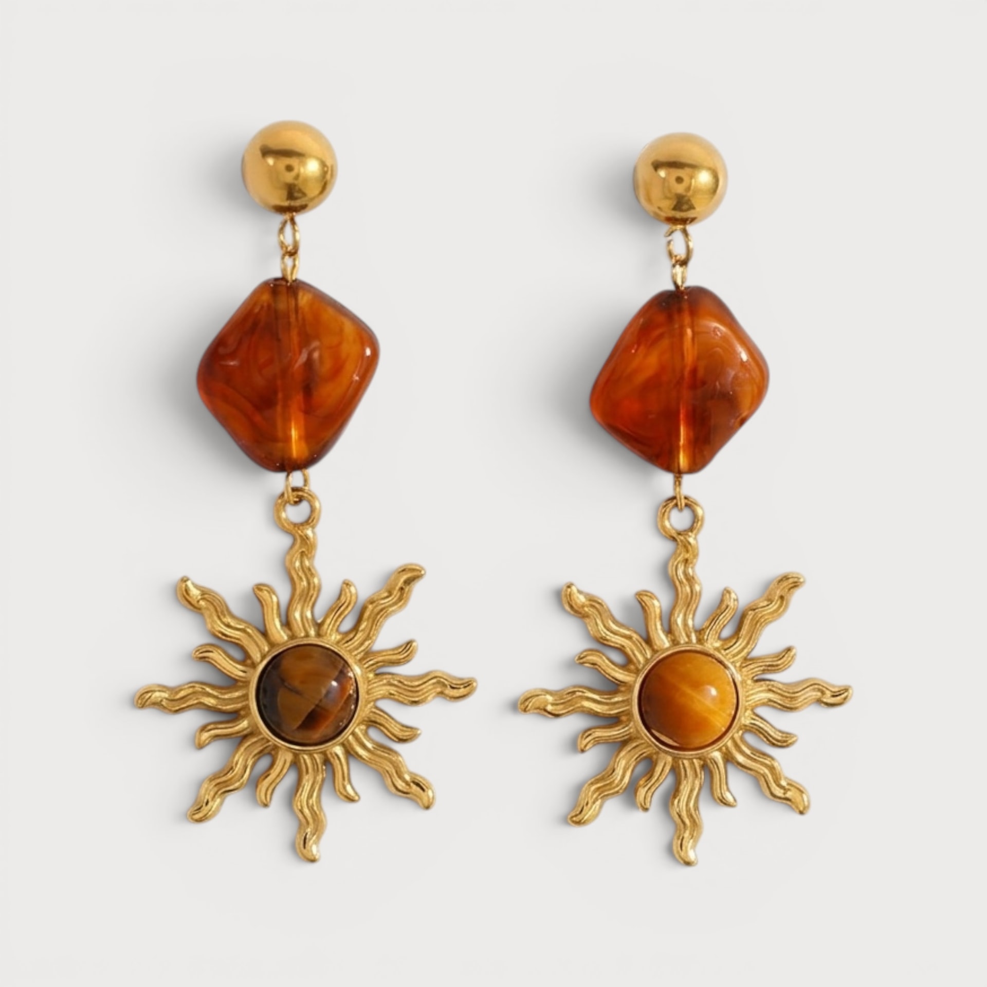 Boucles Houda dorées, pastille et élément ambré au-dessus d’un soleil pendant