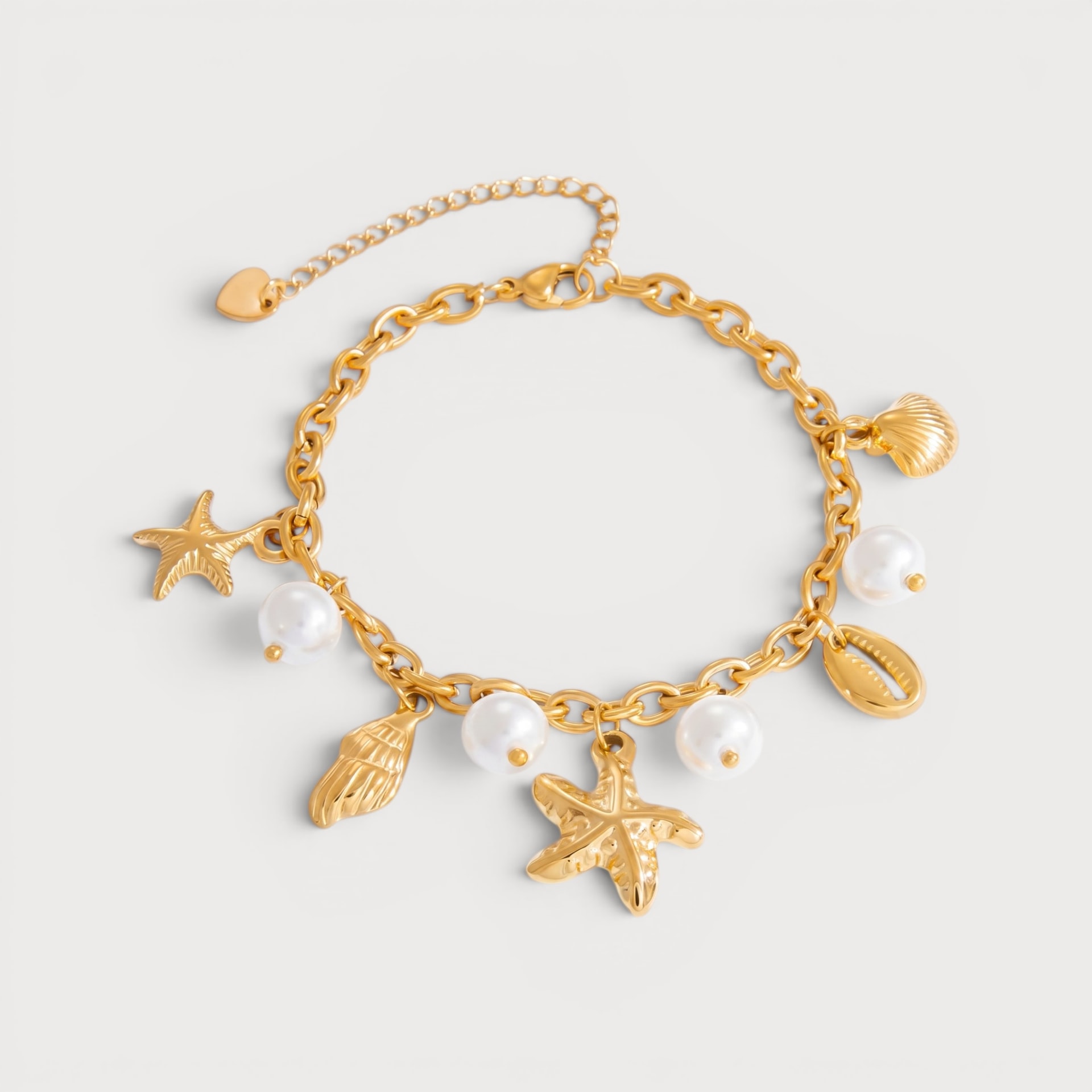 Bracelet Alesandese : des étoiles de mer et des coquillages dorés alternent avec de petites perles blanches sur une chaîne à maillons.