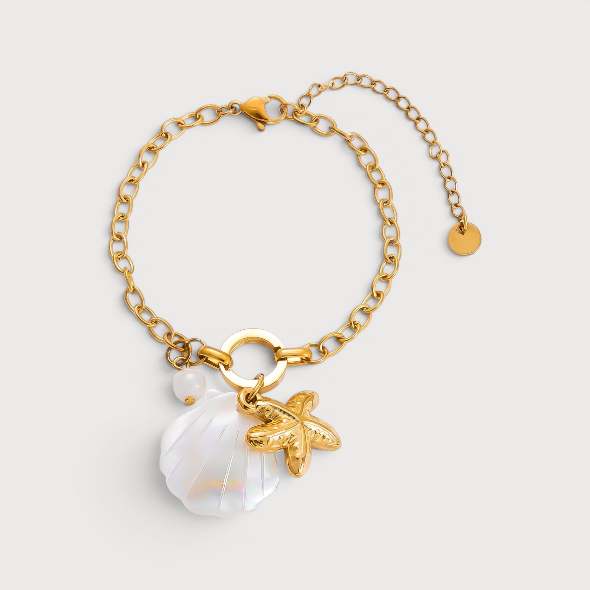 Bracelet Florence : un grand coquillage blanc irisé et une étoile de mer dorée pendent au centre d’une chaîne à maillons.