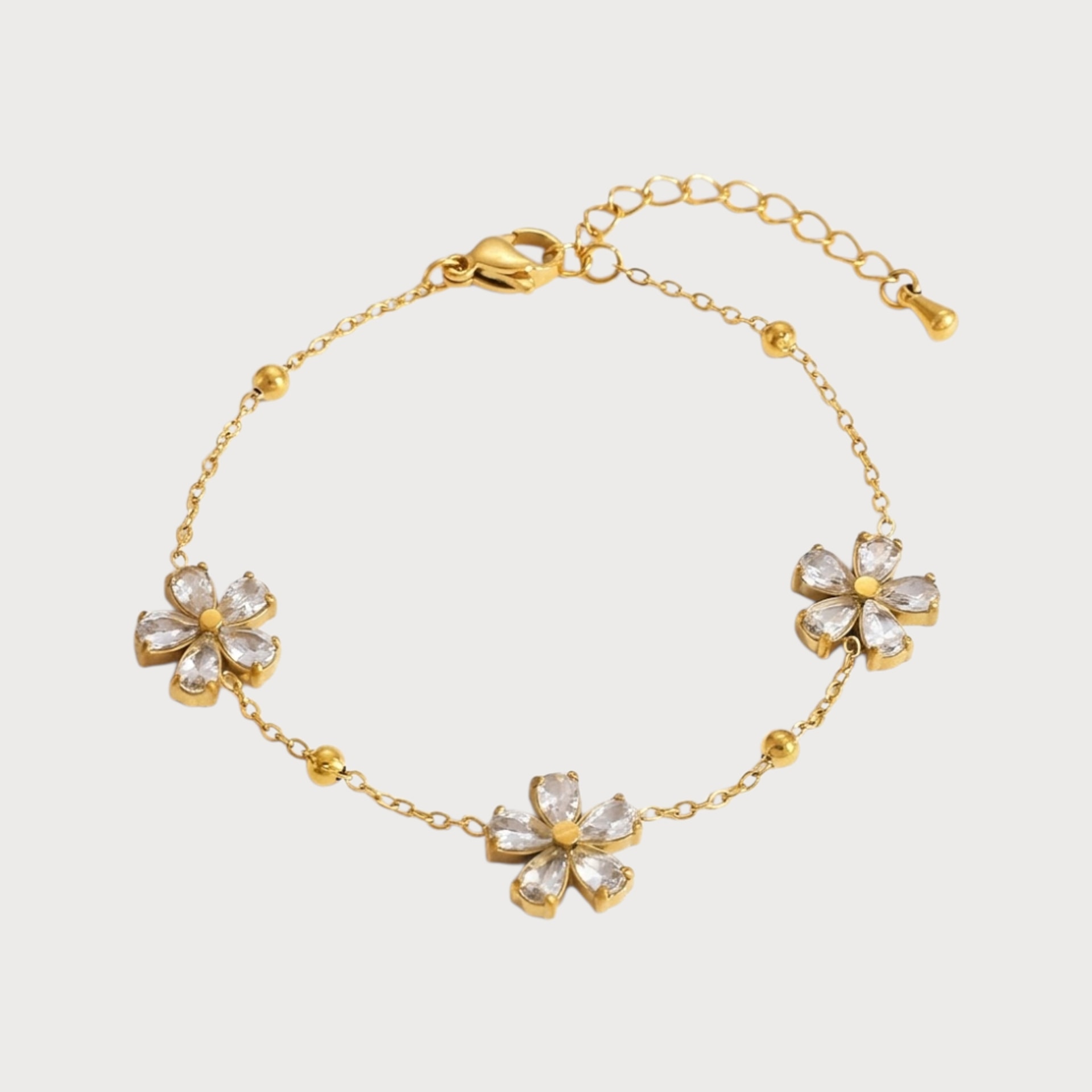 Bracelet Sumaya : une chaîne dorée fine relie trois fleurs aux pétales brillants.