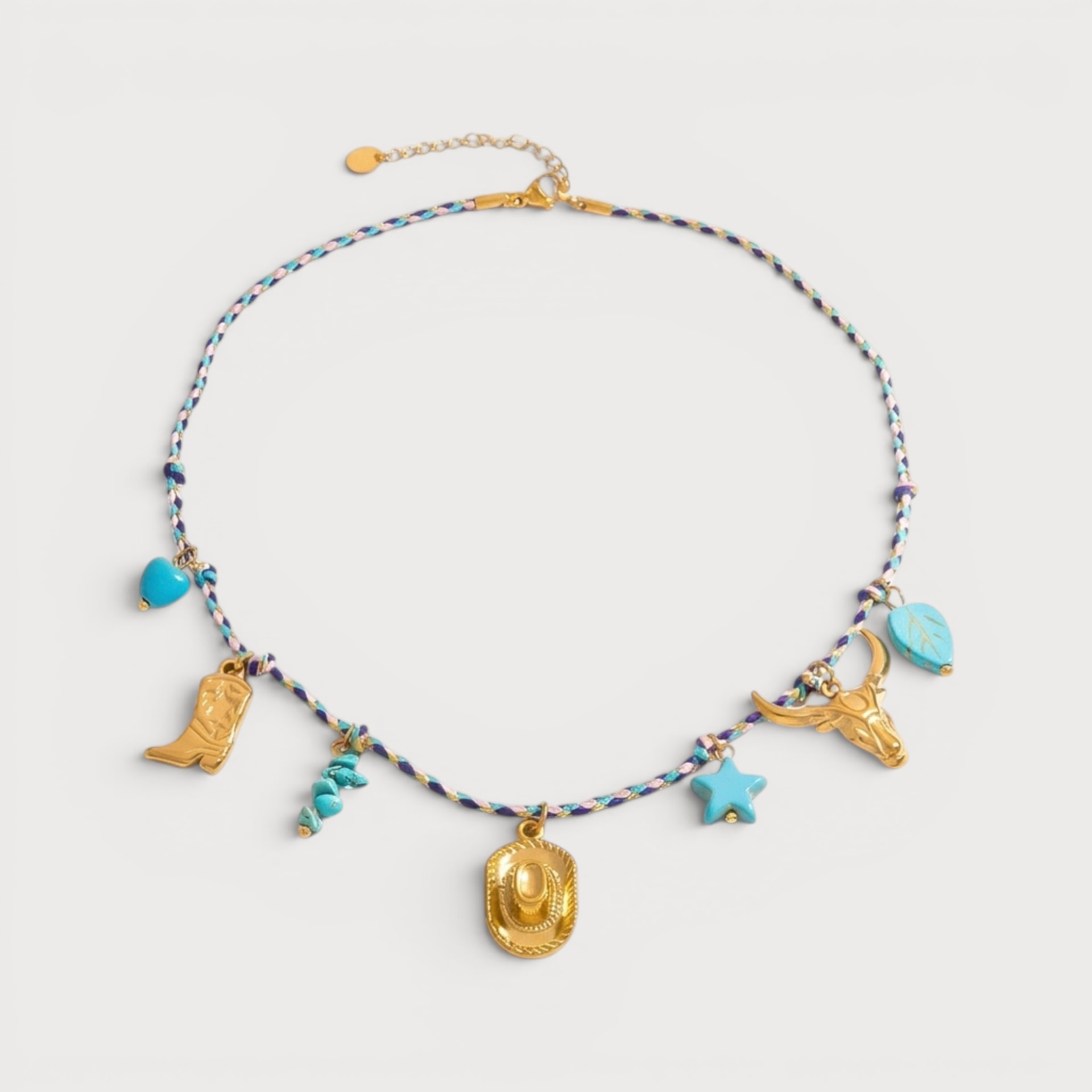 Collier Brigitte : un cordon tressé bleu et blanc porte plusieurs breloques dorées et turquoise, dont un motif coquillage central.