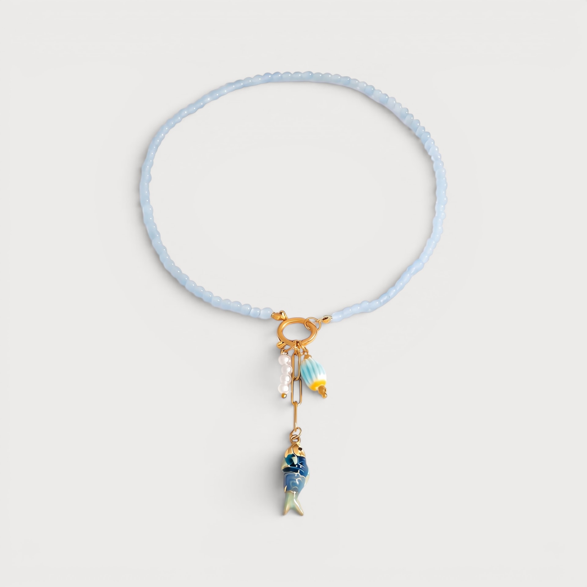 Collier Olivia : un rang de petites perles bleu clair rejoint un fermoir rond doré.